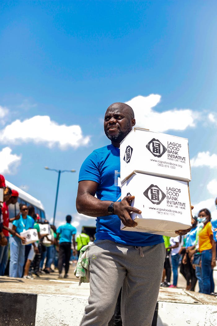 A man participates in food distribution for Lagos Food Bank Initiative under clear blue skies.